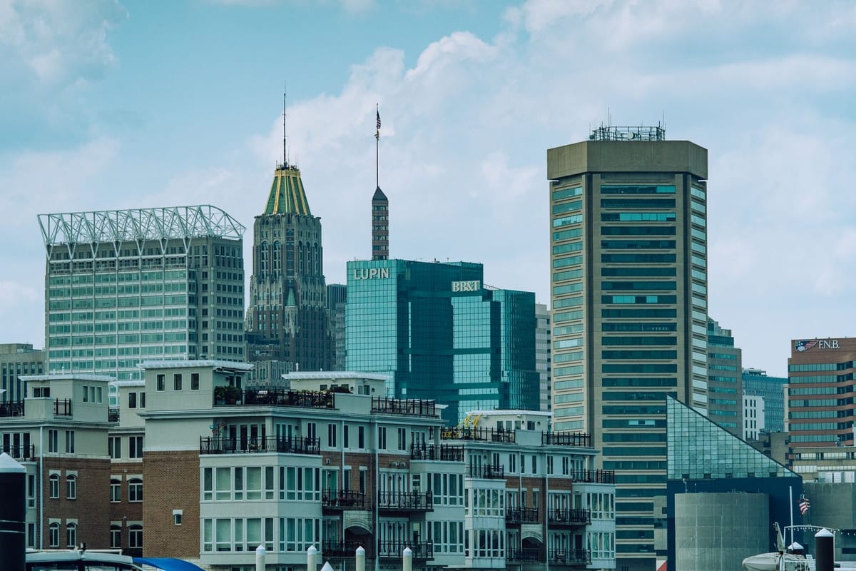 Glass office towers and a pointed-roof tower above waterfront buildings