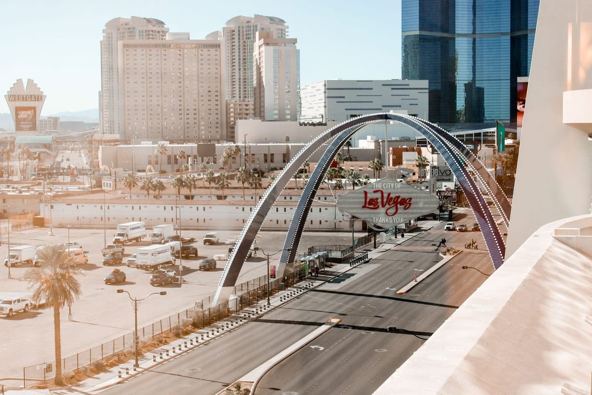 A curved arch spanning a wide road that leads toward large hotel towers