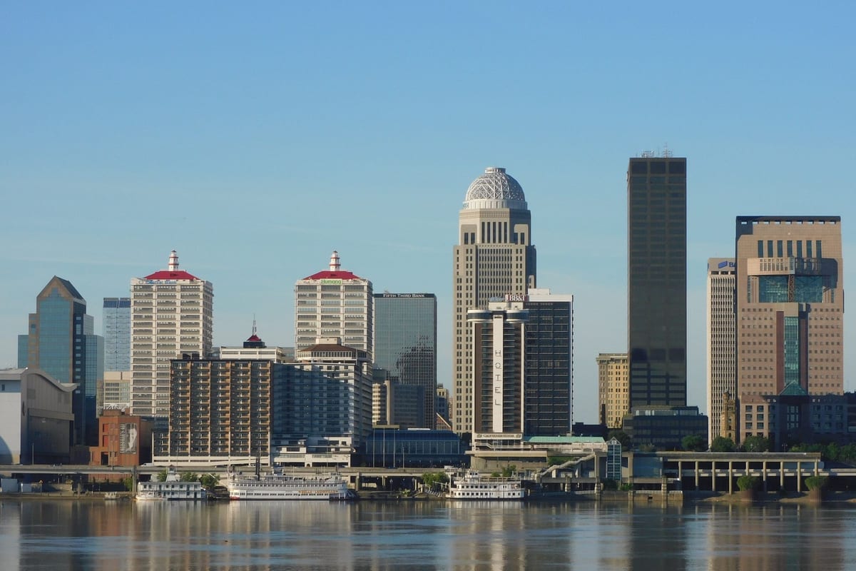 Office towers along a riverfront under a clear sky