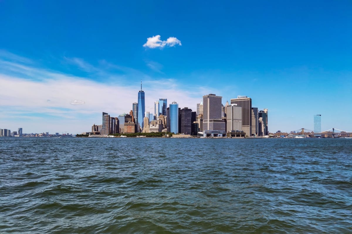 A skyline of towers seen across open, choppy water under a blue sky