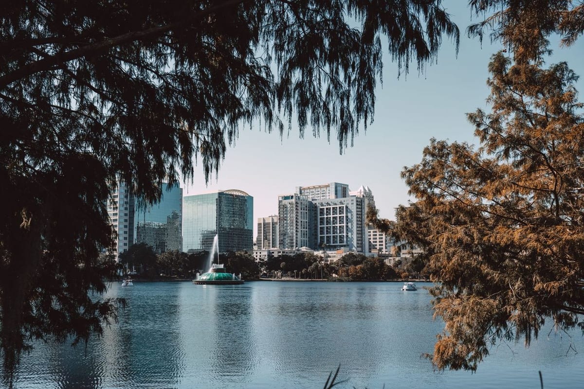 Towers seen across a lake with a fountain, framed by moss-hung trees