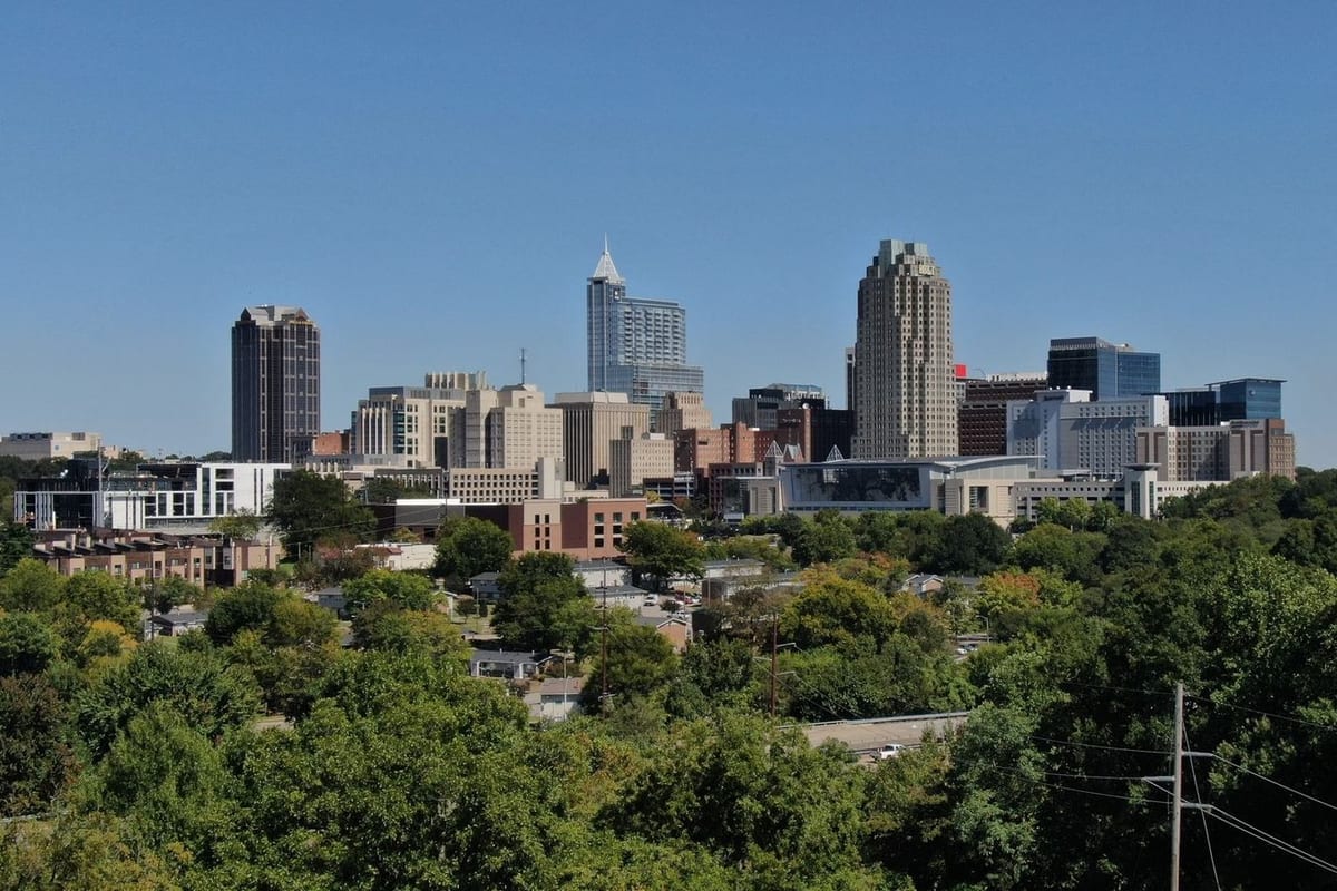 A compact downtown skyline above a hillside of green trees