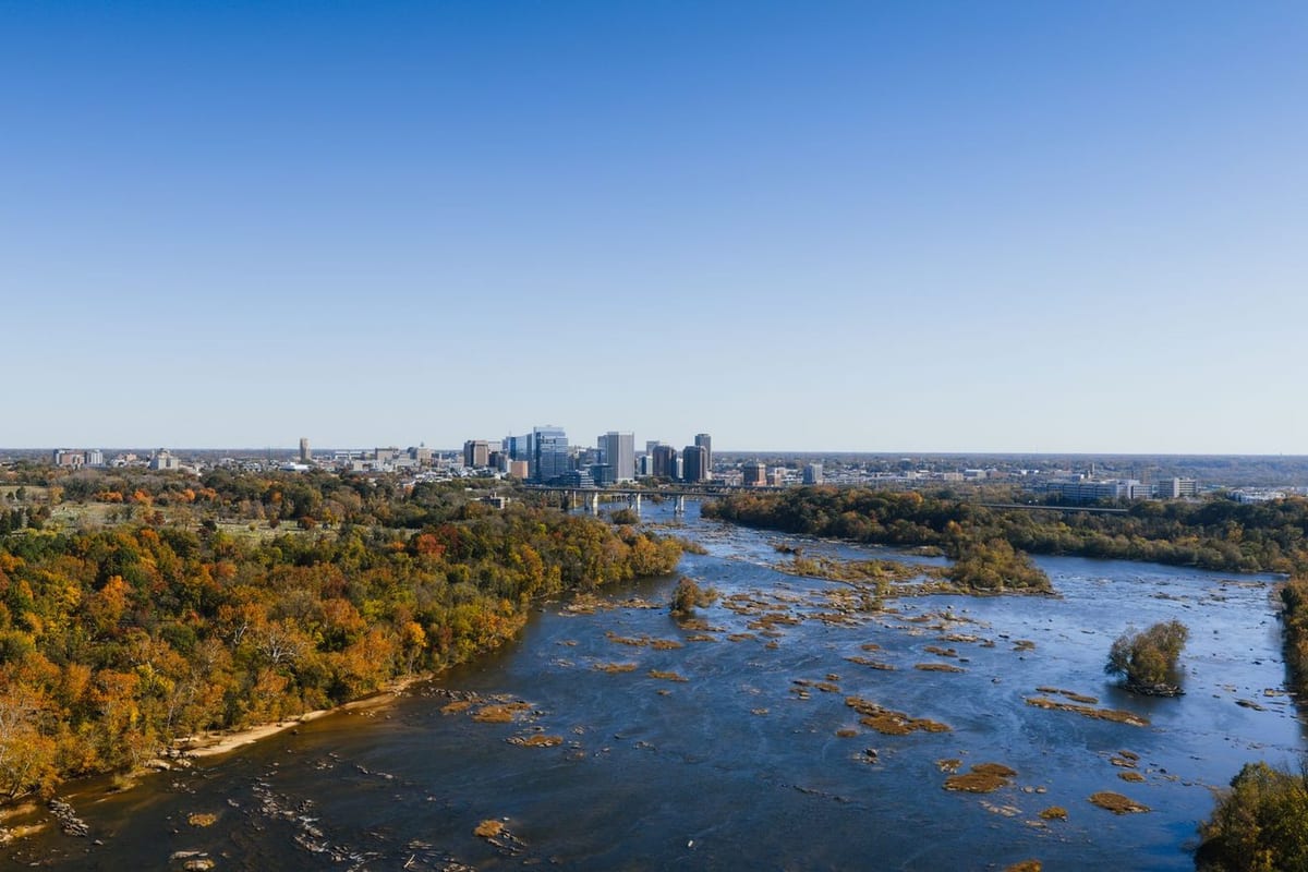 A rocky river running through autumn trees, with a skyline in the distance