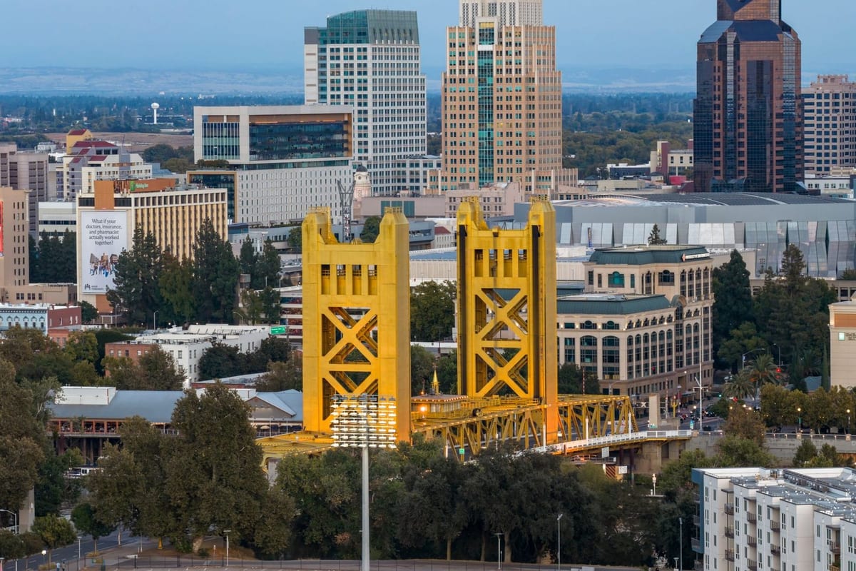 A yellow lift bridge with twin towers in front of a downtown skyline