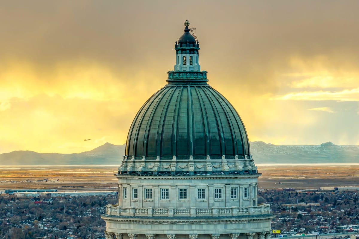 A copper-green dome lit by sunset, with mountains on the horizon