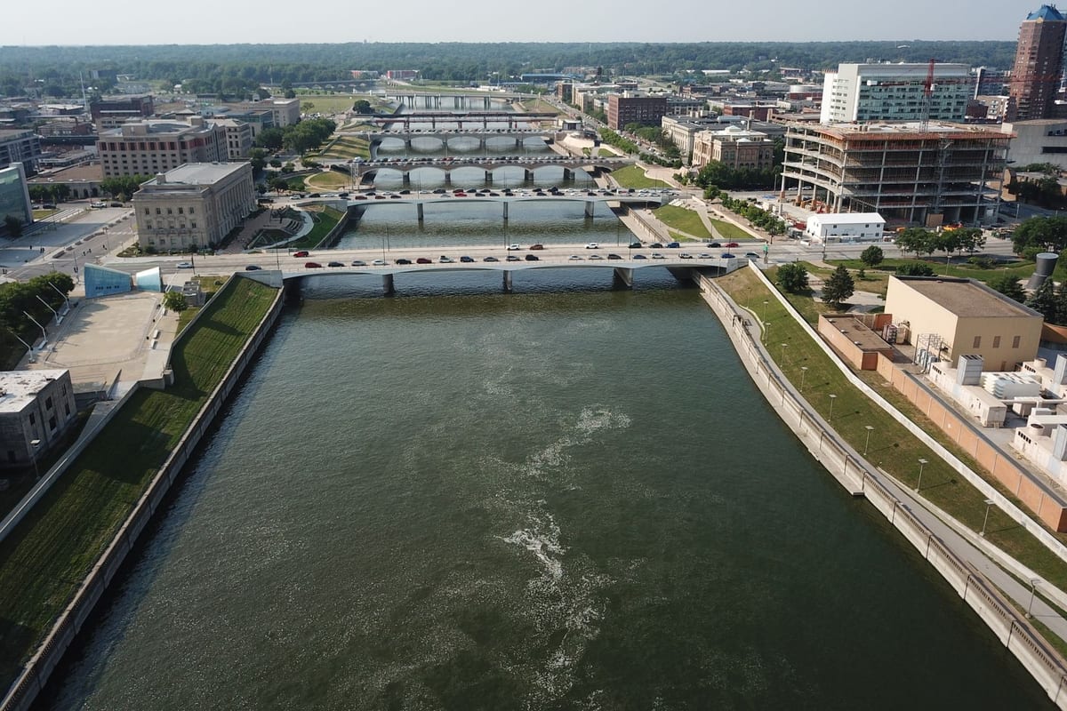 A wide river running through a city past bridges and low buildings, seen from above