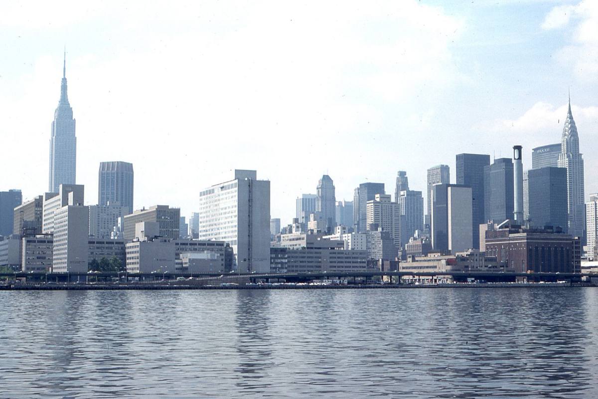 A skyline of towers along a river, a pointed spire rising above the rest